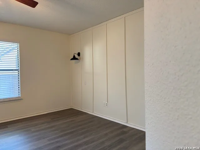 a view of an empty room with wooden floor and closet