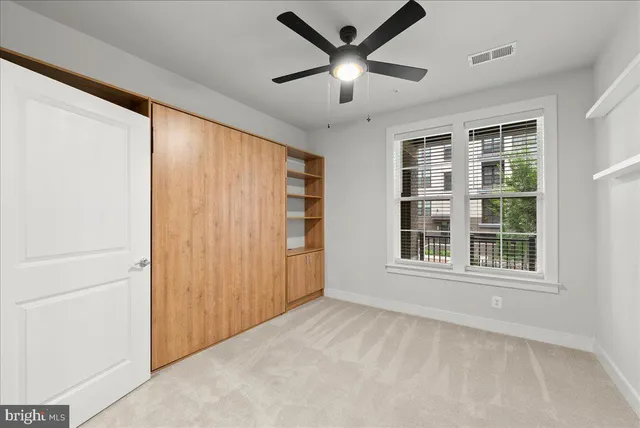 an empty room with window and ceiling fan