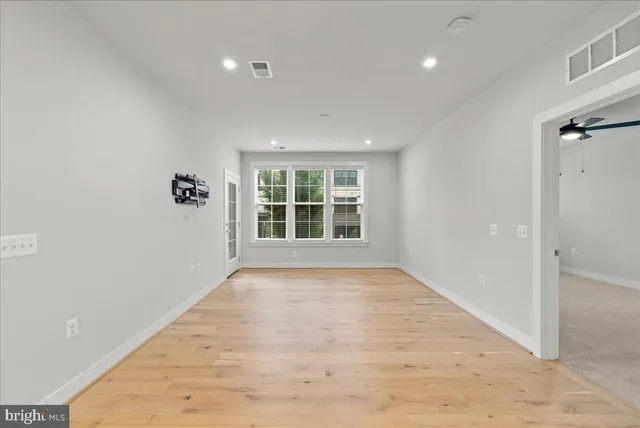 a view of an empty room with wooden floor and a window