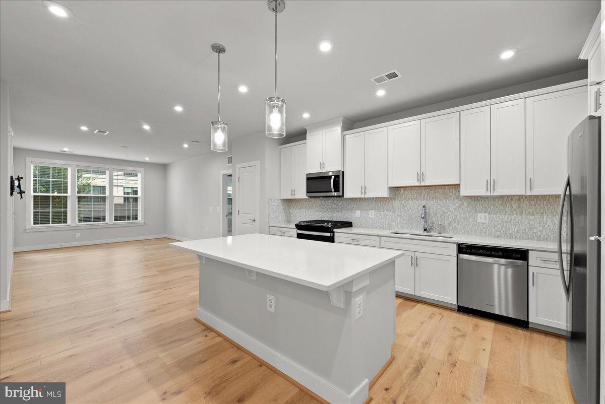 2320 Field Point Road, Unit 103 Herndon, VA 20171 - Photo 2 of 22 a large kitchen with stainless steel appliances granite countertop a stove top oven a sink dishwasher and white cabinets with wooden floor
