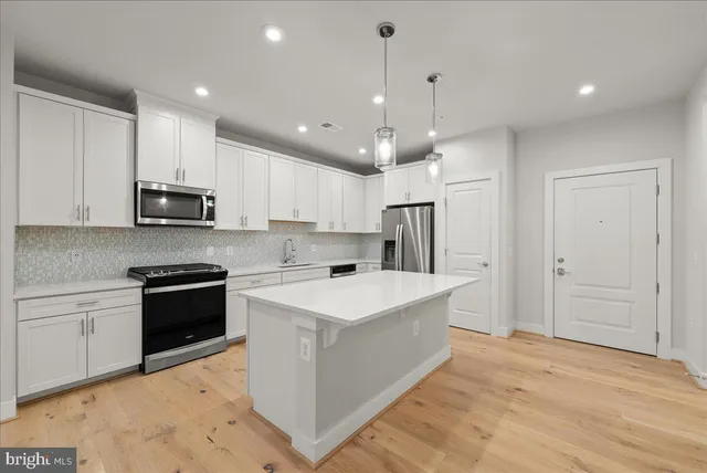 a kitchen with kitchen island a stove a sink and a refrigerator with wooden floor
