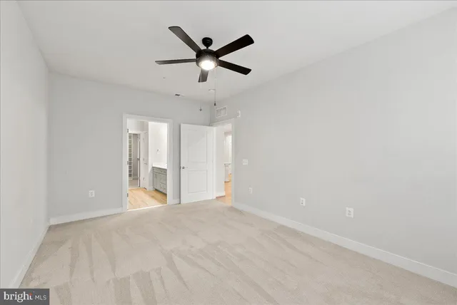 an empty room with ceiling fan and windows