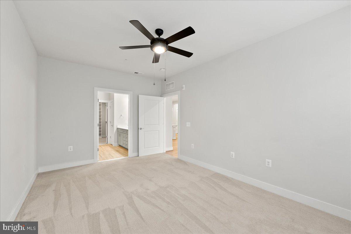 2320 Field Point Road, Unit 103 Herndon, VA 20171 - Photo 7 of 22 an empty room with ceiling fan and windows