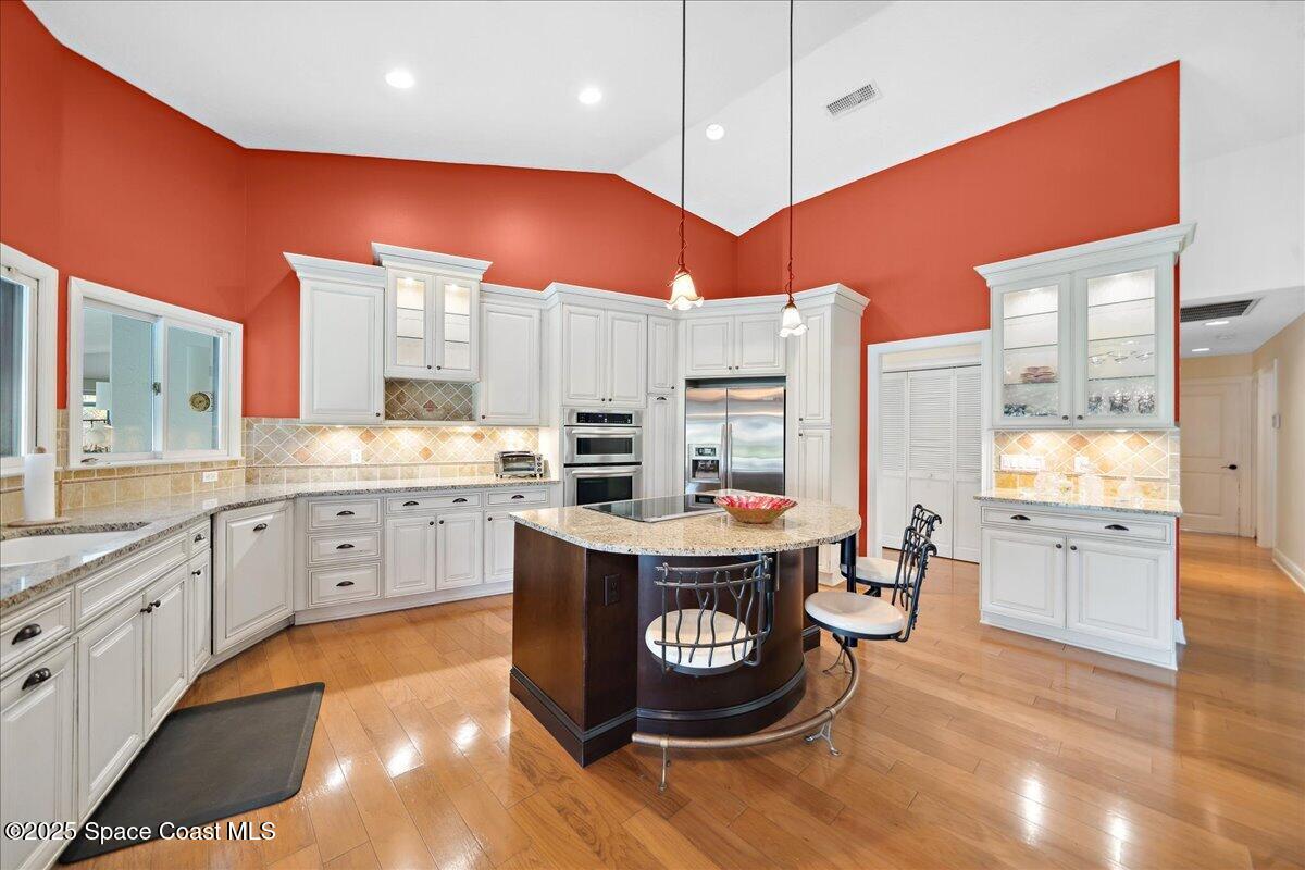 649 Spring Lake Drive Melbourne, FL 32940 - Photo 12 of 47 a kitchen with stainless steel appliances granite countertop a sink a stove and a wooden floors