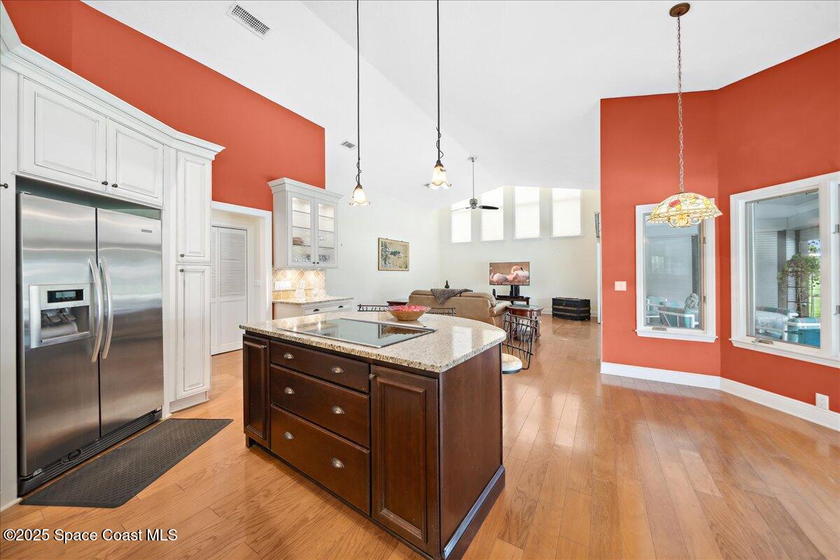 649 Spring Lake Drive Melbourne, FL 32940 - Photo 14 of 47 a kitchen with stainless steel appliances granite countertop a refrigerator a stove and a sink with wooden floor