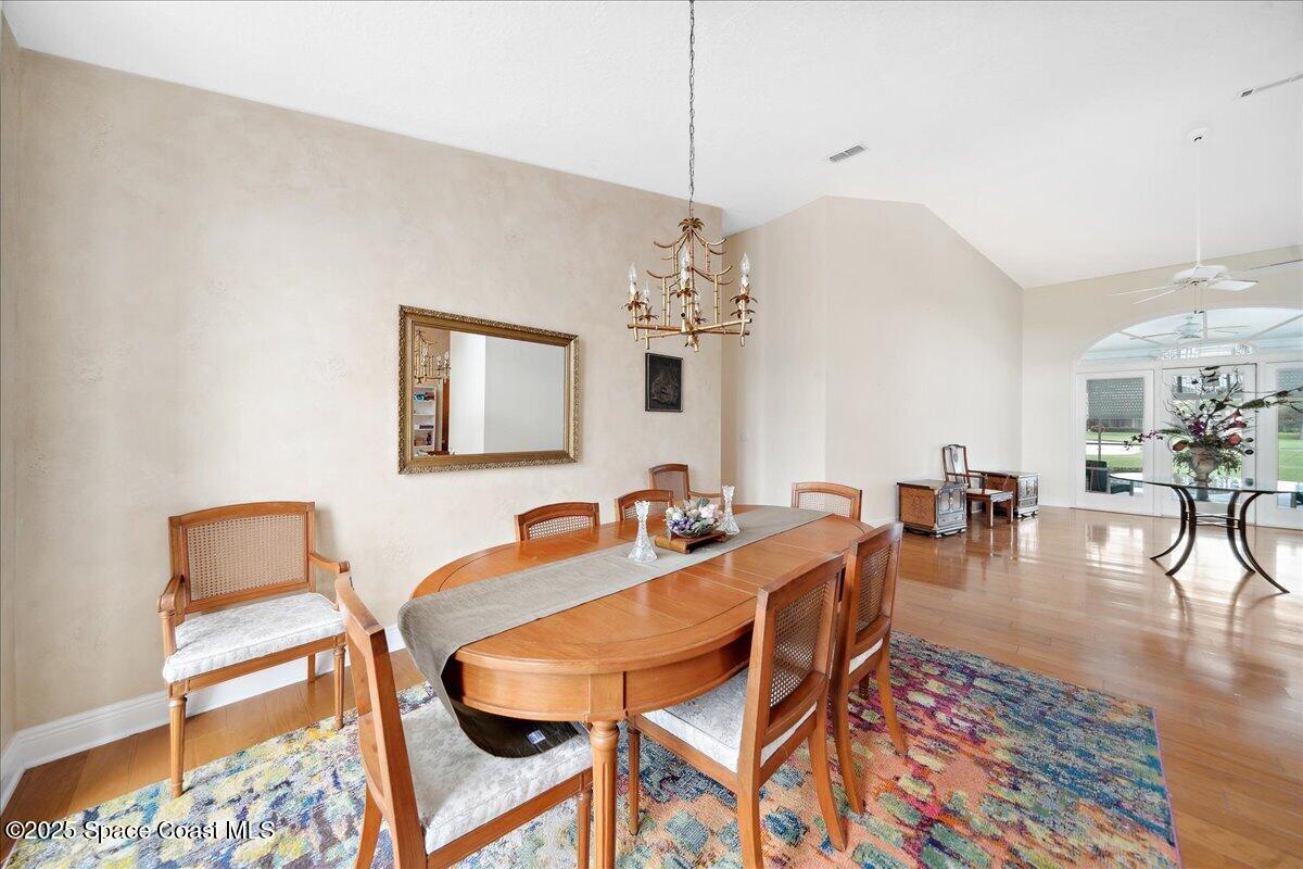 649 Spring Lake Drive Melbourne, FL 32940 - Photo 9 of 47 a dining room with wooden floor a chandelier a glass table and chairs