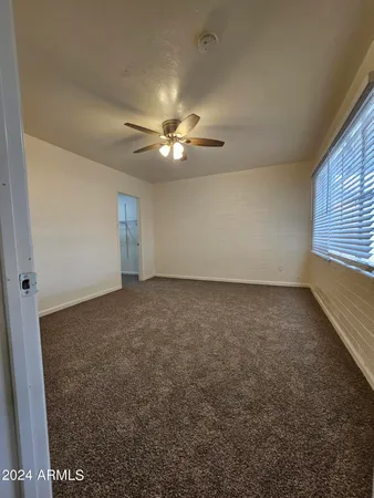 an empty room with windows and fan