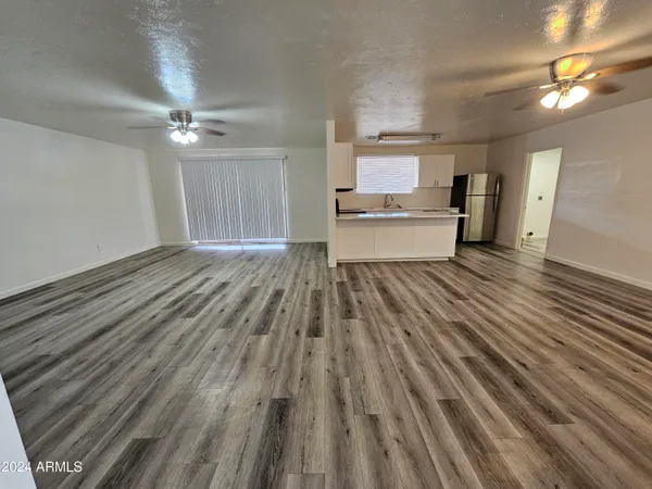 a view of kitchen and empty room with wooden floor