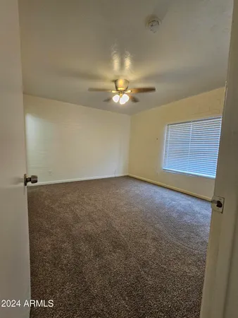 an empty room with a ceiling fan and a window