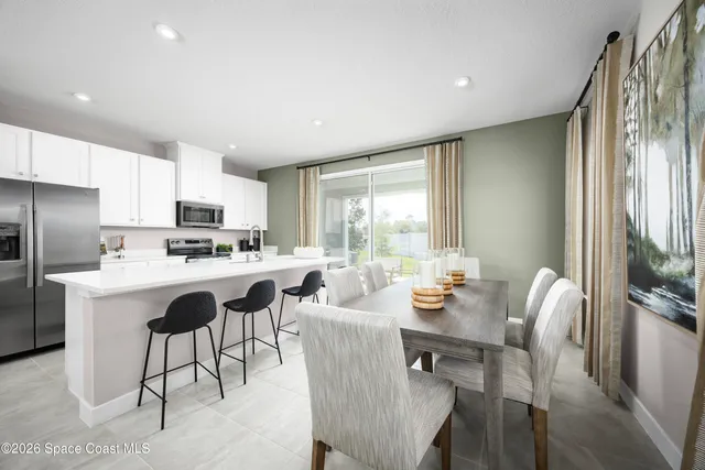 a living room with stainless steel appliances granite countertop furniture a fireplace a flat screen tv and a refrigerator