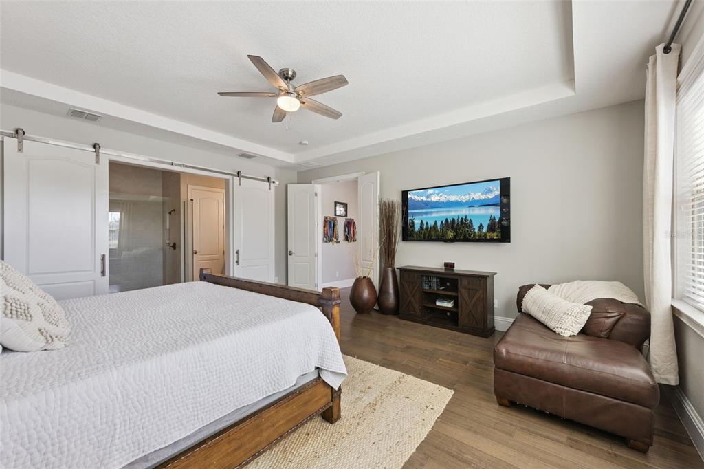 13436 Heswall Run Orlando, FL 32832 - Photo 16 of 72 a spacious bedroom with a bed a couch and a flat screen tv