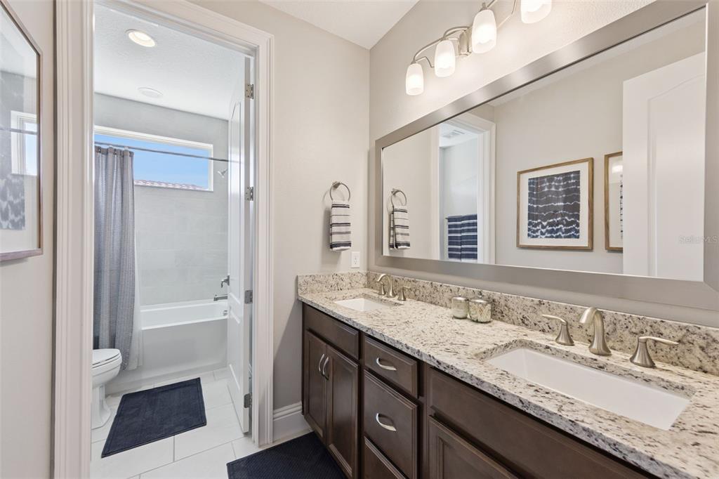 13436 Heswall Run Orlando, FL 32832 - Photo 26 of 72 a bathroom with a granite countertop sink double vanity and a mirror