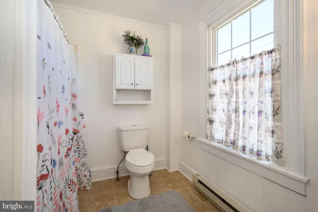 a white toilet sitting next to a window in a bathroom
