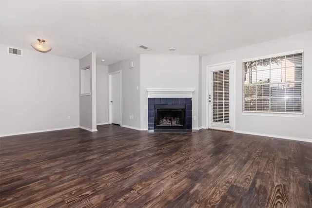 an empty room with wooden floor fireplace and windows