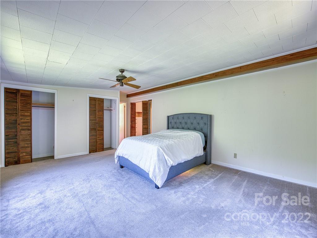 5474 Soco Road Maggie Valley, NC 28751 - Photo 16 of 48 a spacious bedroom with a bed and a chandelier