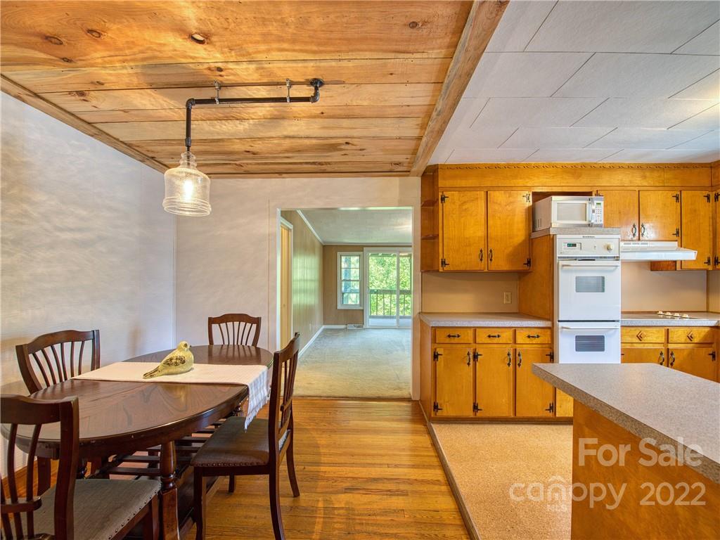 5474 Soco Road Maggie Valley, NC 28751 - Photo 9 of 48 a dining hall with stainless steel appliances kitchen island granite countertop a table chairs and a wooden floor