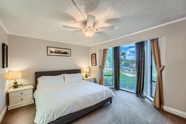 a bedroom with a large bed and a chandelier fan