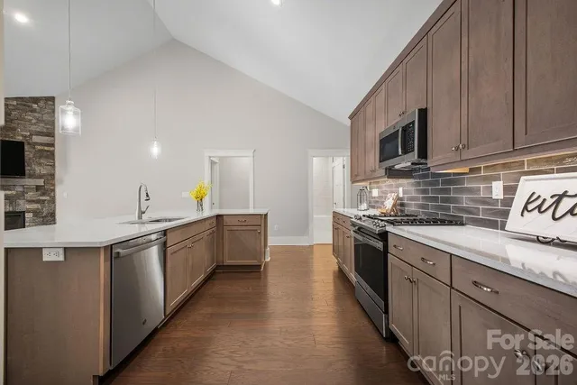 a large kitchen with stainless steel appliances granite countertop a sink and dishwasher a stove top oven with wooden floor