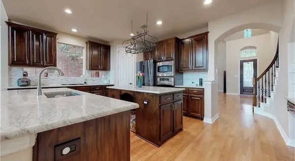 a kitchen with granite countertop a sink a counter top space and stainless steel appliances