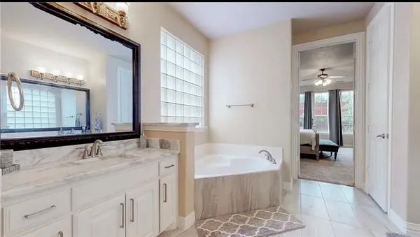 a bathroom with a granite countertop tub sink and mirror