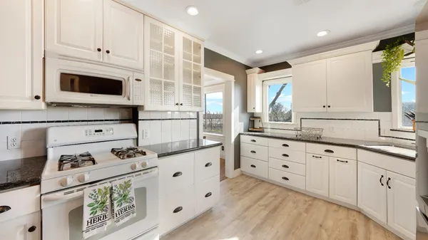 a kitchen with granite countertop white cabinets and white appliances