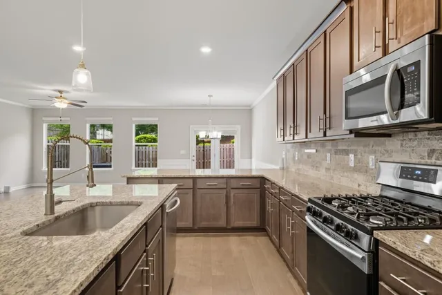 a large white kitchen with kitchen island a sink stainless steel appliances and cabinets