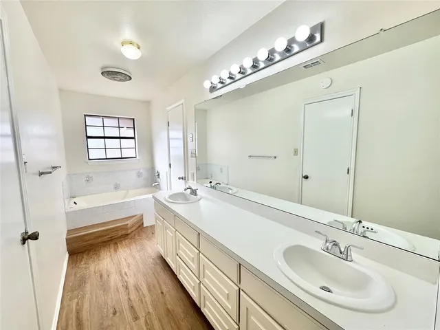 a bathroom with a tub sink and mirror