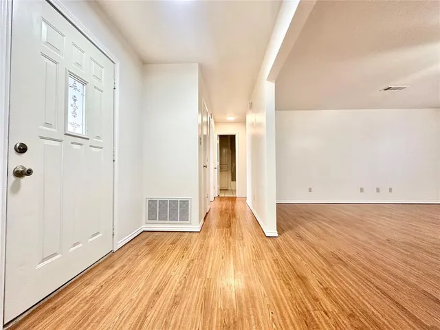 a view of a big room with wooden floor and windows