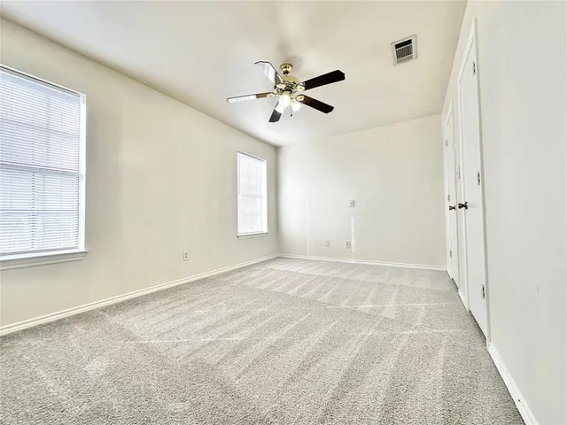 an empty room with windows and fan