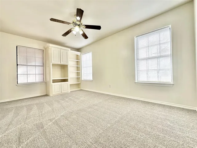an empty room with windows and ceiling fan