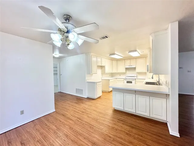 a view of a kitchen with kitchen island a sink wooden floor and a refrigerator