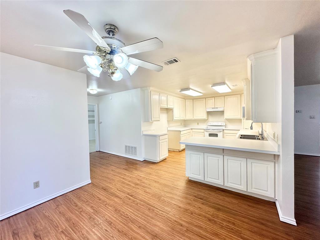 8869 Liberty Road Aubrey, TX 76227 - Photo 7 of 25 a view of a kitchen with kitchen island a sink wooden floor and a refrigerator