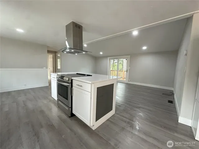 a kitchen with stove and wooden floor