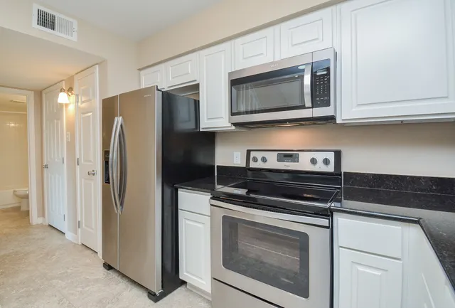 a kitchen with stainless steel appliances white cabinets and a stove top oven