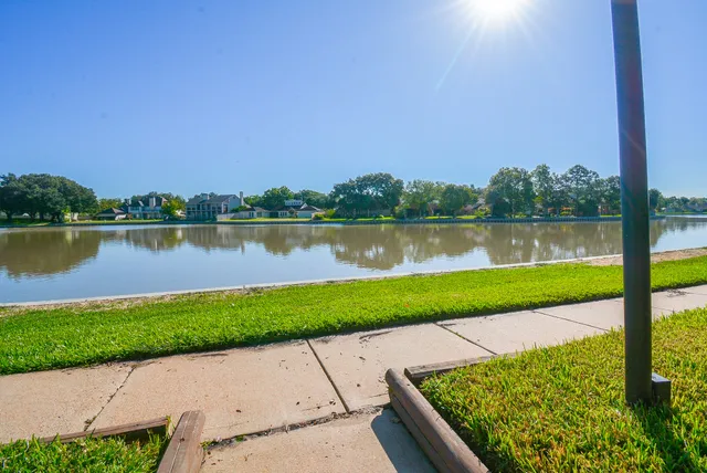 a view of a lake with a big yard and large trees