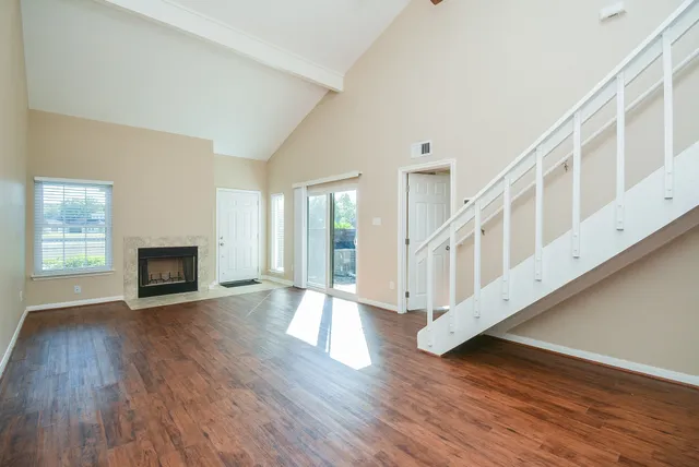 a view of an empty room with wooden floor fireplace and a window