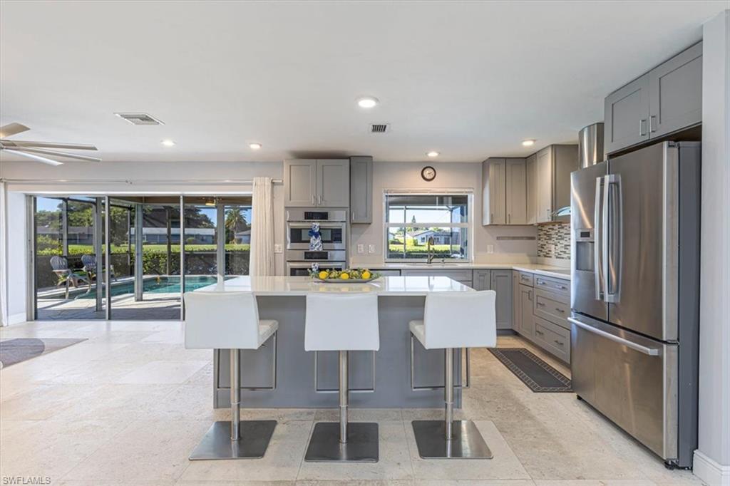 4590 Eagle Key Circle Naples, FL 34112 - Photo 3 of 37 Kitchen featuring gray cabinets, appliances with stainless steel finishes, a breakfast bar, a kitchen island, and recessed lighting