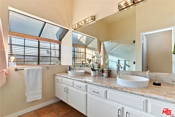 a bathroom with a granite countertop sink and a large mirror