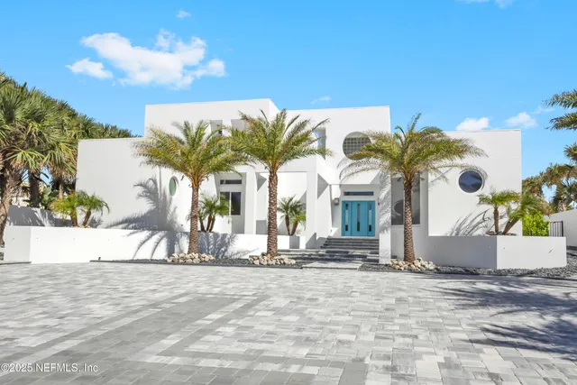 a view of a white house with a yard and palm trees