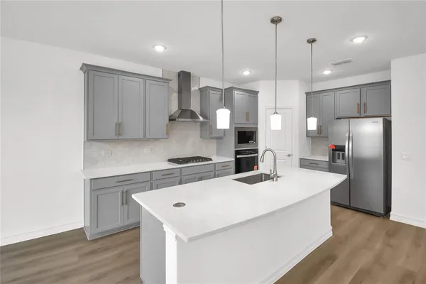 a kitchen with a refrigerator a sink and wooden floor