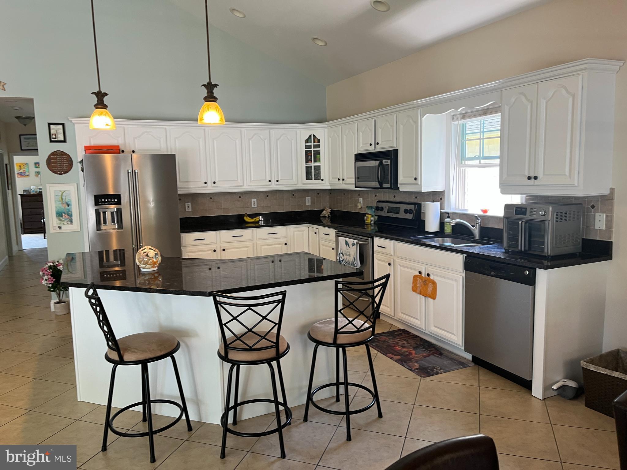 3816 Chestnut Road Baltimore, MD 21220 - Photo 14 of 27 a kitchen with stainless steel appliances kitchen island granite countertop a dining table chairs and a refrigerator