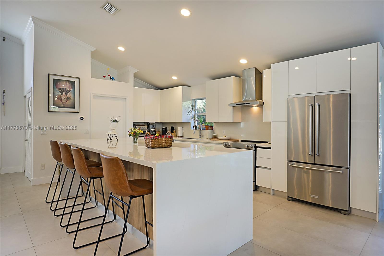 8919 Byron Avenue Surfside, FL 33154 - Photo 11 of 51 a kitchen with stainless steel appliances a refrigerator a stove a sink and a dining table with wooden floor