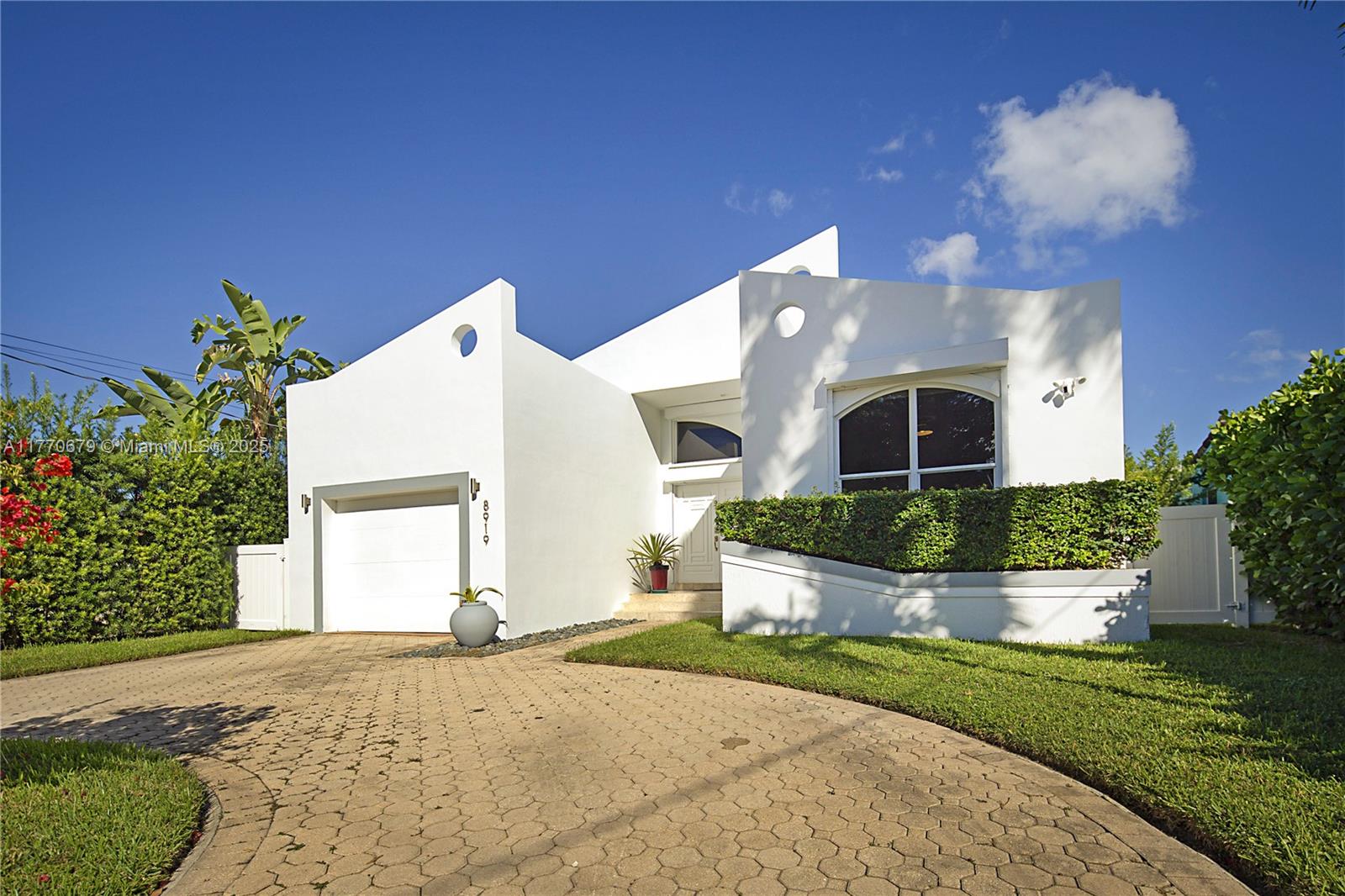 8919 Byron Avenue Surfside, FL 33154 - Photo 2 of 51 a front view of a house with a yard and potted plants