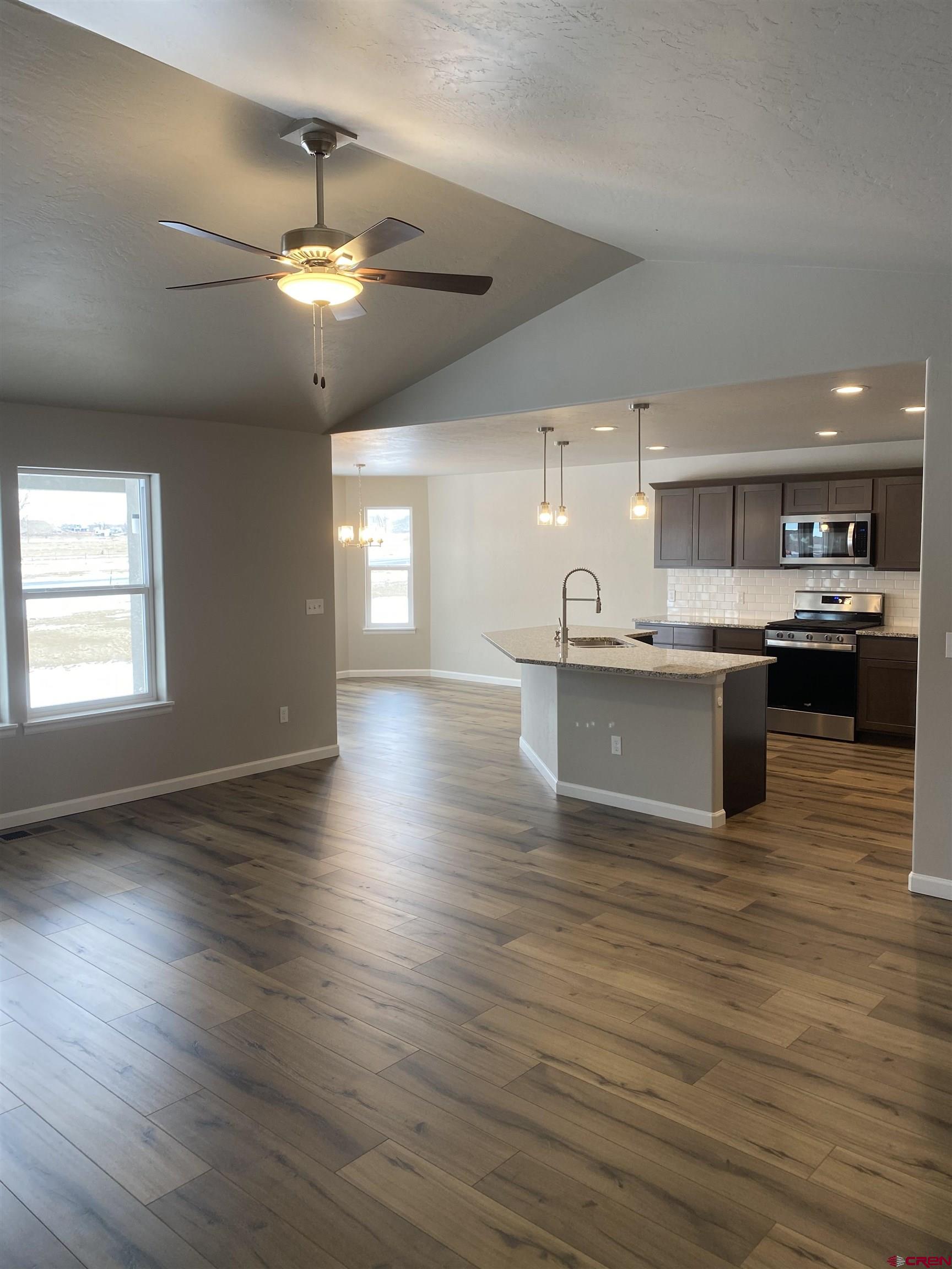 3674 Big Pines Loop Montrose, CO 81401 - Photo 11 of 19 a large kitchen with stainless steel appliances granite countertop a stove top oven a sink dishwasher a dining table and chairs with wooden floor