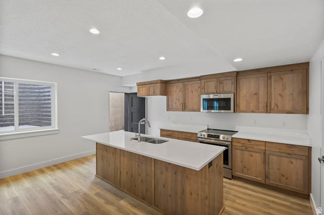 728 East Mountain Road North Ogden, UT 84414 - Photo 18 of 28 Bright kitchen featuring a central island with an undermount sink, light countertops, wood-finish flooring, and recessed lighting