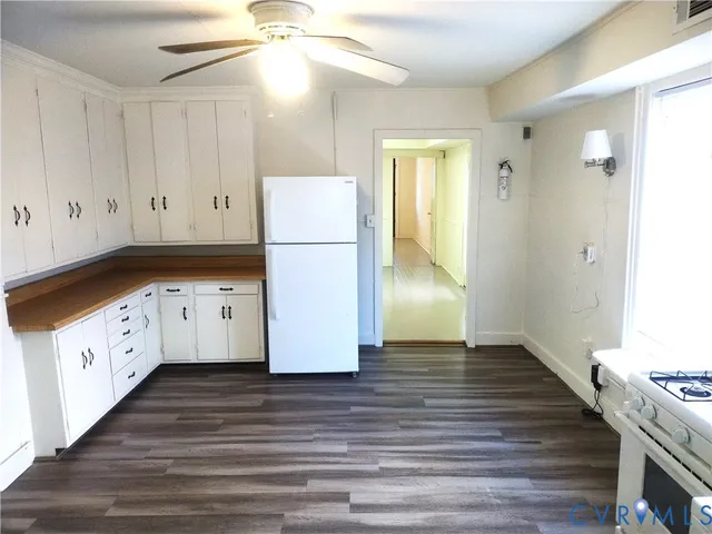 a kitchen with cabinets appliances wooden floor and a window