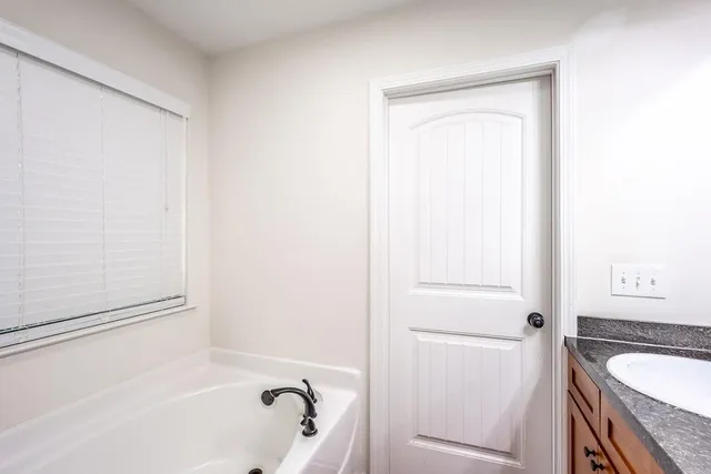 a bathroom with a granite countertop sink and a bathtub