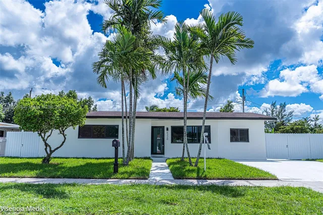 a palm tree sitting in front of a house with a yard
