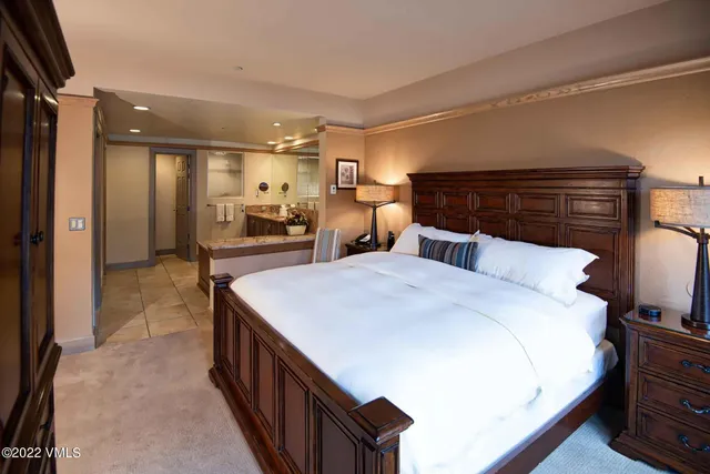 a large bedroom with a bed and a large mirror on the dresser