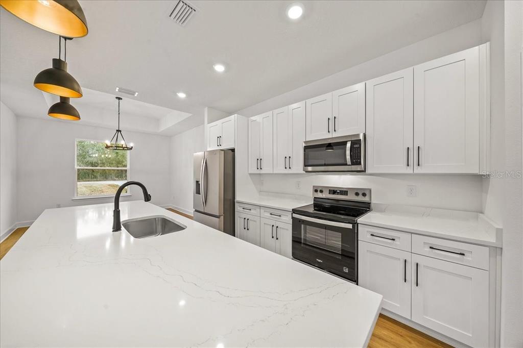 11088 Fulton Avenue Weeki Wachee, FL 34613 - Photo 12 of 63 a kitchen with granite countertop a sink stainless steel appliances and white cabinets